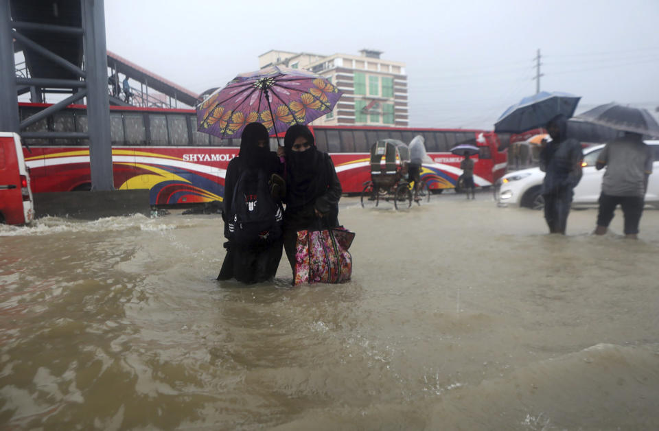People wade through flooded waters in Sylhet, Bangladesh, Saturday, June 18, 2022. At least 18 people have died as floods cut a swatch across northeastern India and Bangladesh, leaving millions of homes underwater. Both countries have asked the military to help with the severe flooding, which could worsen because rains are expected to continue over the weekend. (AP Photo/Abdul Goni)