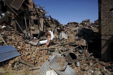 A woman carrying a sack of belongings walks amidst the rubble of collapsed houses after Saturday's earthquake in Bhaktapur, Nepal April 27, 2015. REUTERS/Navesh Chitrakar