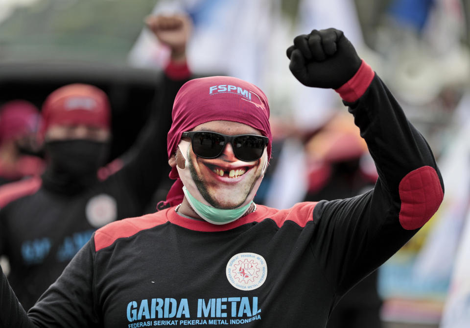 A worker wearing mask as a precaution against coronavirus outbreak, raises his fist as he shouts slogans during a May Day rally in Jakarta, Indonesia, Saturday, May 1, 2021. Workers in Indonesia marked international labor day on Saturday curtailed by strict limits on public gatherings to express anger at a new law they say could harm labor rights and welfare. (AP Photo/Dita Alangkara)