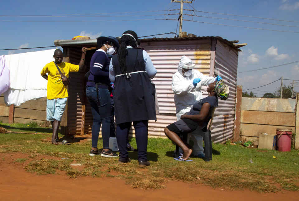 Health workers collect a sample for coronavirus testing, outside a shack during the screening and testing campaign aimed to combat the spread of COVID-19 at Lenasia South, south Johannesburg, April 21, 2020. (AP Photo/Themba Hadebe)