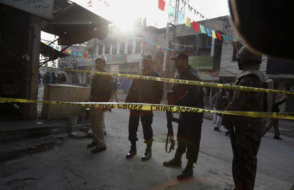 Pakistani police officers and army soldier secure a street close to the site of a suicide bombing in Rawalpindi, Pakistan on Monday, Jan. 20, 2014. A suicide bomber blew himself up not far from Pakistan's military headquarters Monday, killing more than a dozen people a day after a Taliban bombing inside an army compound in the northwest of the country killed many troops, officials and militants said. (AP Photo/Anjum Naveed)