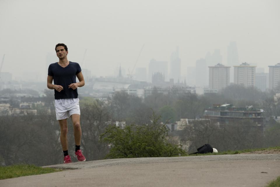 A man jogs up Primrose Hill as buildings in central London stand shrouded in smog, Thursday, April 3, 2014. European pollution and dust swirling in from the Sahara created a "perfect storm" of smog in Britain on Wednesday, prompting authorities to warn people with heart or lung conditions to cut down on tough physical exercise outdoors. Air pollution in some areas reached the top rung on its 10-point scale, the environment department said. (AP Photo/Matt Dunham)