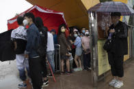 Visitors wearing mask to curb the spread of the coronavirus takes shelter from a sudden rainstorm in Beijing on Saturday, May 23, 2020. New coronavirus cases dropped to zero in China for the first time Saturday but overwhelmed hospitals across Latin America – both in countries lax about lockdowns and those lauded for firm, early confinement. (AP Photo/Ng Han Guan)