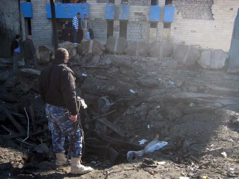 Security forces and civilians gather at a crater caused by a suicide car bomb attack in Kirkuk, 180 miles (290 kilometers) north of Baghdad, Iraq, Tuesday, Jan. 7, 2014. Police said a suicide bomber rammed his explosives-laden truck into a police station, killing and wounding scores of people in the northern city, home to a mix of Arabs, Kurds and Turkomen, each of the ethnic groups has competing claims to the oil-rich area. (AP Photo/Emad Matti)