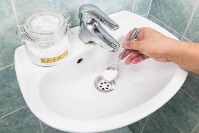 Baking soda being poured into sink drain to unclog