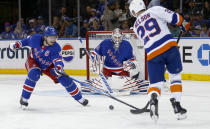 New York Rangers goalie Igor Shesterkin, center, maintains his focus as Rangers defenseman Jacob Trouba, left, knocks the puck away from New York Islanders center Brock Nelson, right, during the second period of an NHL hockey game Saturday, April 13, 2024, in New York. (AP Photo/John Munson)