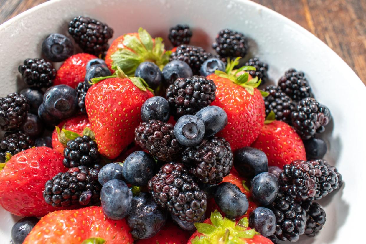 bowl of strawberries, blueberries, and blackberries flat lay with copy space