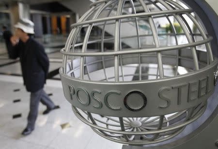 A man walks past a logo of steelmaker POSCO at the company's headquarters in Seoul October 25, 2010. REUTERS/Truth Leem/Files