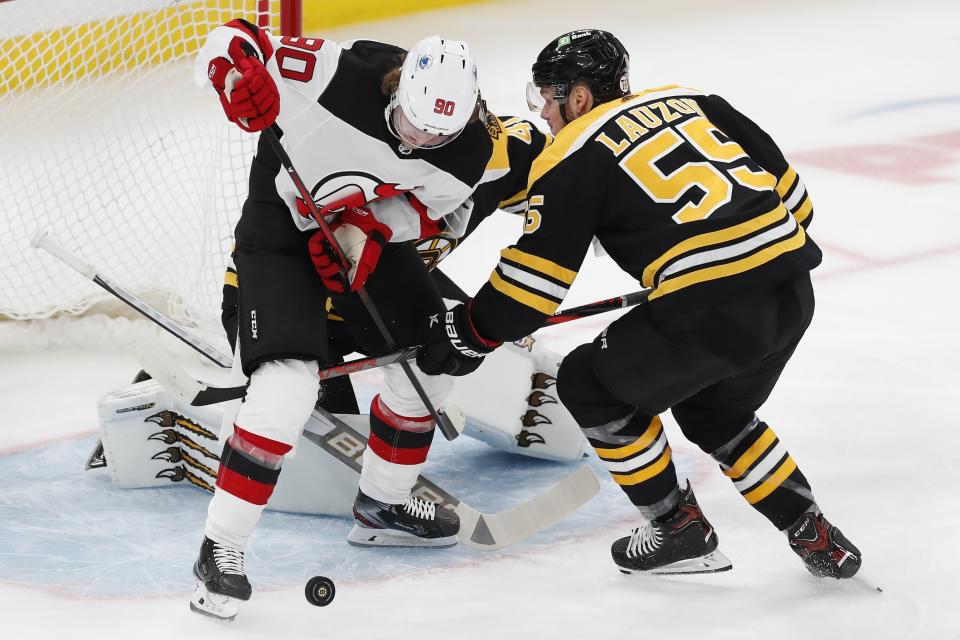 New Jersey Devils' Jesper Boqvist (90) and Boston Bruins' Jeremy Lauzon (55) battle for the puck during the first period of an NHL hockey game, Sunday, March 28, 2021, in Boston. (AP Photo/Michael Dwyer)