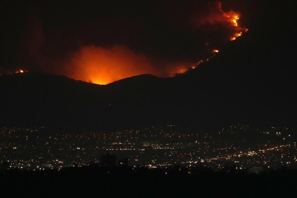 Flames burn a forest during a wildfire on Parnitha mountain near Hasia suburb, northwestern Athens, Tuesday, Aug. 22, 2023. Hundreds of firefighters battle dozens of wildfires across the country, fanned by gale-force winds. (AP Photo/Thanassis Stavrakis)