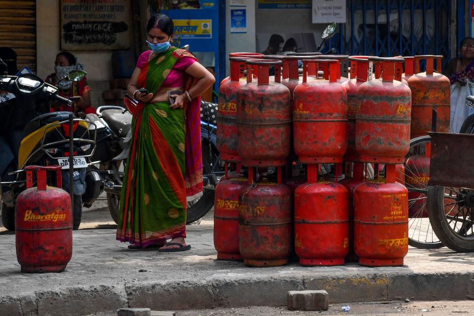 A woman checks her mobile phone as she waits to collect a gas cylinder outside a shop during a government-imposed nationwide lockdown as a preventive measure against the COVID-19 coronavirus in Mumbai on March 26, 2020. (Photo by INDRANIL MUKHERJEE / AFP) (Photo by INDRANIL MUKHERJEE/AFP via Getty Images)