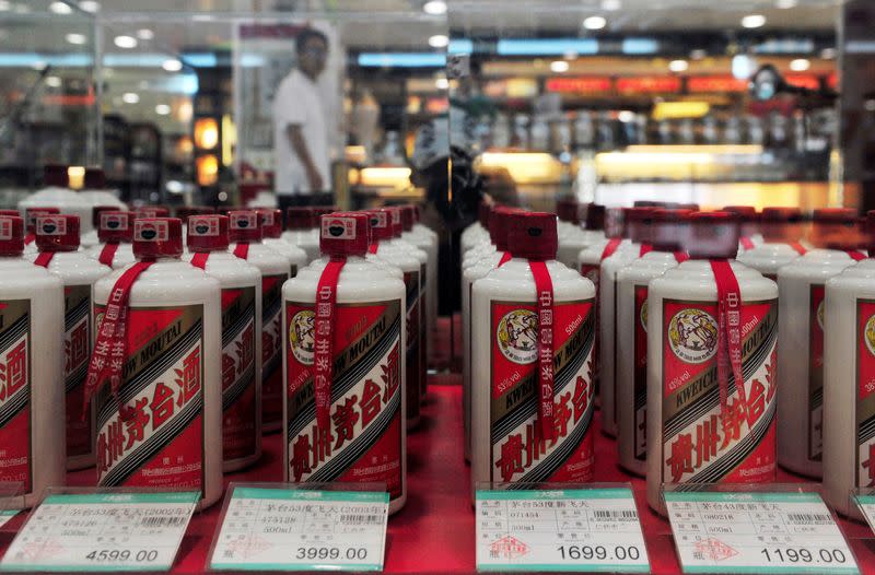 FILE PHOTO: A customer walks past a glass case displaying Maotai liquors with different price tags at a supermarket in Shenyang