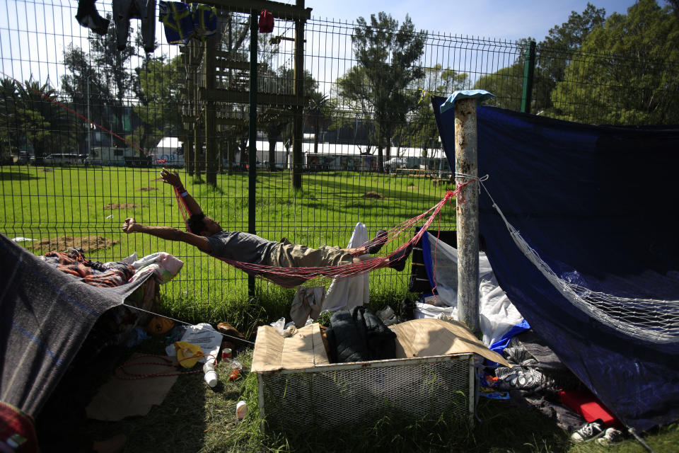 A man stretches as he awakens in a hammock at the sports complex where thousands of migrants have been camped out for several days in Mexico City, Friday, Nov. 9, 2018. About 500 Central American migrants headed out of Mexico City on Friday to embark on the longest and most dangerous leg of their journey to the U.S. border, while thousands more were waiting one day more at a massive improvised shelter. (AP Photo/Rebecca Blackwell)