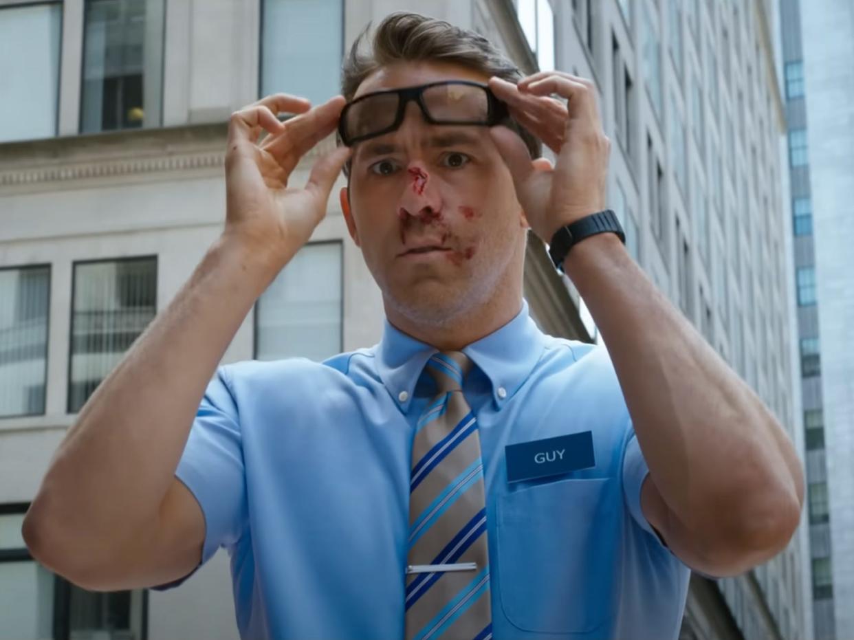 Ryan Reynolds with blood on his face lifting his glasses up in "Free Guy."