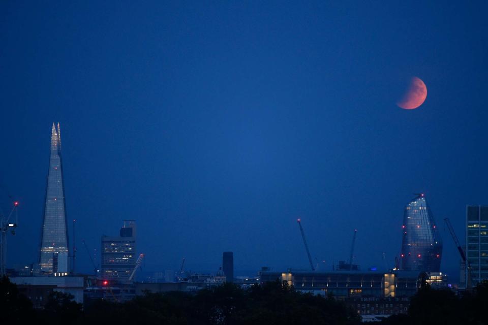 A partial lunar eclipse appears over the London skyline (Getty Images)