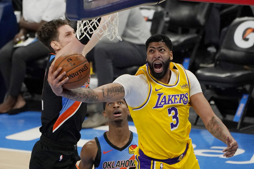 Los Angeles Lakers forward Anthony Davis (3) goes to the basket in front of Oklahoma City Thunder center Mike Muscala, left, and guard Shai Gilgeous-Alexander during the second half of an NBA basketball game Wednesday, Jan. 13, 2021, in Oklahoma City. (AP Photo/Sue Ogrocki)