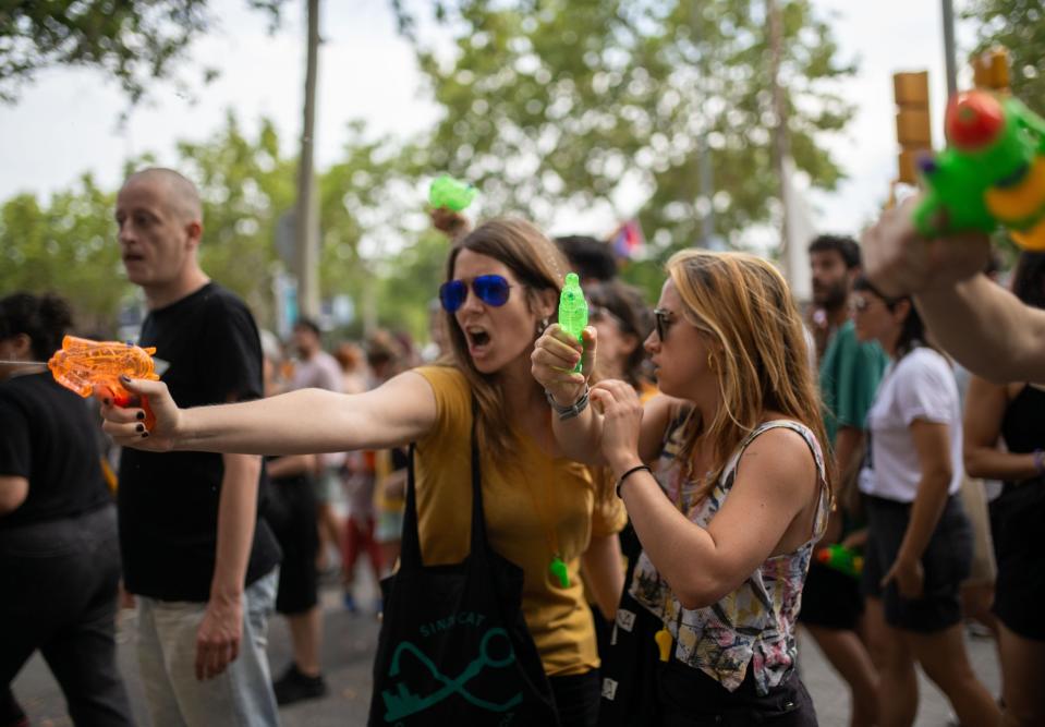 Two women with water guns among a crowd of protesters.