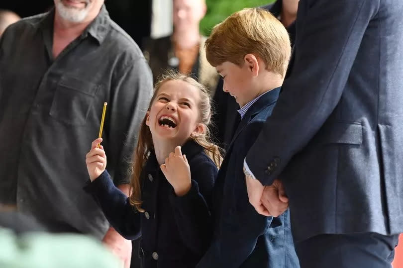 Princess Charlotte of Cambridge laughs as she conducts a band next to her brother Prince George of Cambridge during a visit to Cardiff Castle