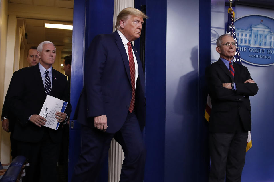 President Donald Trump arrives with Vice President Mike Pence to give a White House coronavirus briefing on March 25, as Dr. Anthony Fauci, director of the National Institute of Allergy and Infectious Diseases, watches.