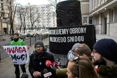 Greenpeace activists demonstrate on a street following the decision of the Court of Justice of the European Union (CJEU), after they handed a big, carbon cake to Poland's Energy Mister Krzysztof Tchorzewski as a symbol of 'protecting Polish smog', in Warsaw, Poland February 22, 2018. The banner reads: 'Attention smog!'. Agencja Gazeta/Dawid Zuchowicz via REUTERS