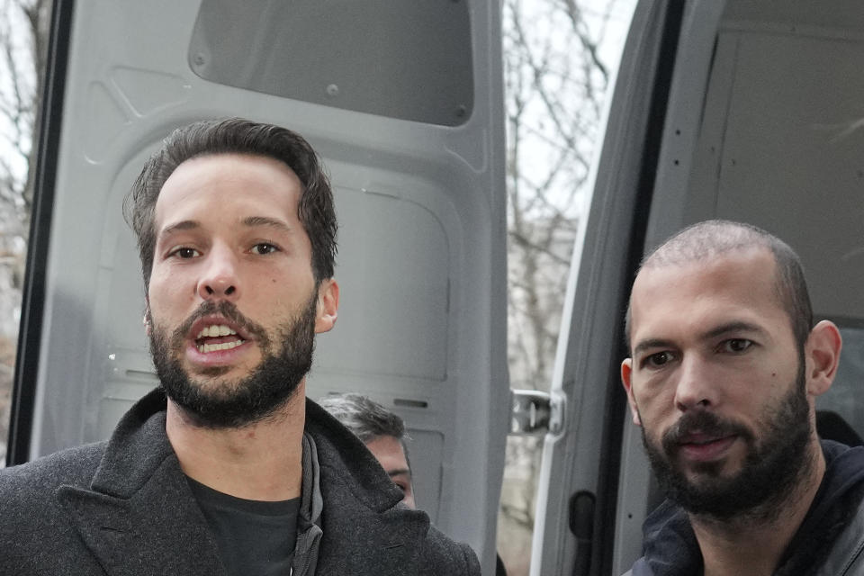 Police officers escort Andrew Tate, right, handcuffed to his brother Tristan, outside the Directorate for Investigating Organized Crime and Terrorism (DIICOT) where prosecutors examine electronic equipment confiscated during the investigation in their case, in Bucharest, Romania, Thursday, Jan. 26, 2023. Divisive influencer Andrew Tate and his brother Tristan, are held on charges of being part of an organized crime group, human trafficking and rape. (AP Photo/Vadim Ghirda)