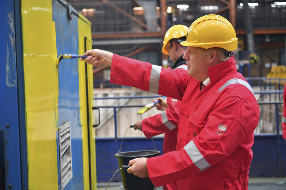 Britain's Prime Minister Boris Johnson helps out with the painting of an electrical generator with Sam Evans, during his visit to Appledore Shipyard in Devon, England, Tuesday, Aug. 25, 2020. (Ben Birchall/PA via AP)