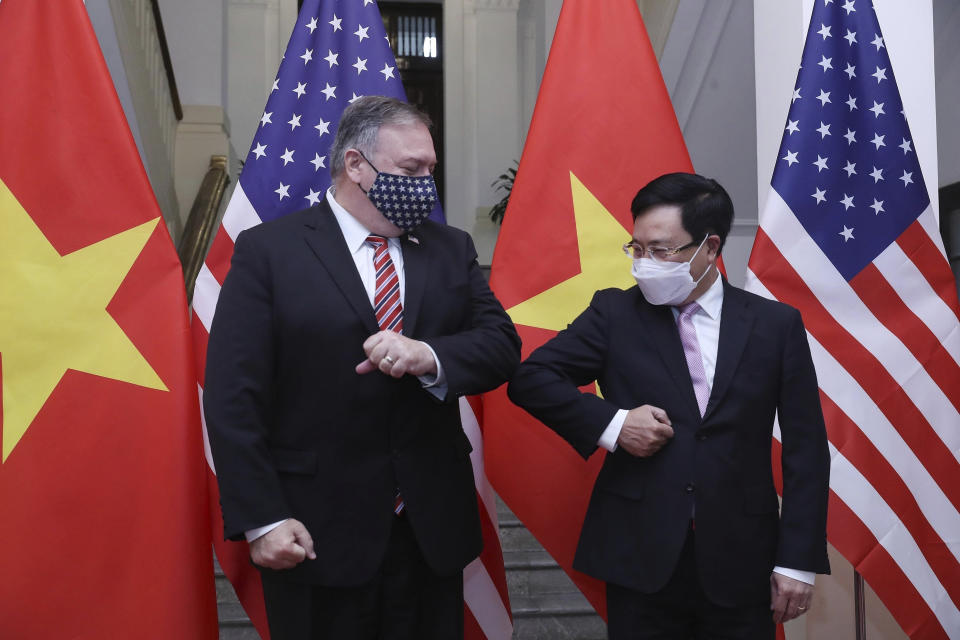 U.S. Secretary of State Mike Pompeo, left, and Vietnamese Foreign Minister Pham Binh Minh gesture with their elbows before a meeting in Hanoi, Vietnam, Friday, Oct. 30, 2020. Pompeo is wrapping up an anti-China tour of Asia in Vietnam as the fierce American presidential election race enters its final stretch. (Bui Lam Khanh/VNA via AP)