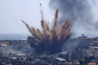 Humo y restos salen despedidos tras ataques aéreos israelíes contra un edificio en Gaza, el jueves 13 de mayo de 2021. (AP Foto/Hatem Moussa)