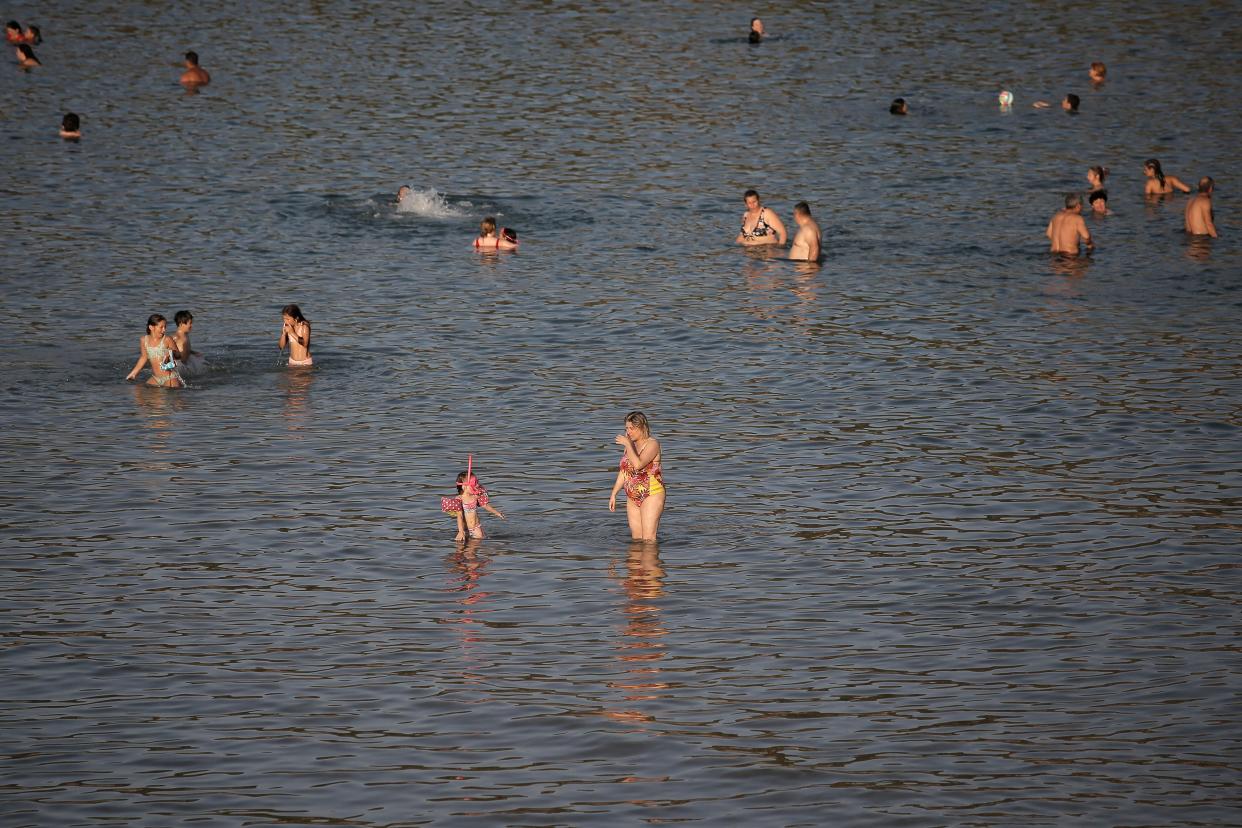 People in Greece take to the beach to cool down on the coast of Varkiza near Athens (EPA)