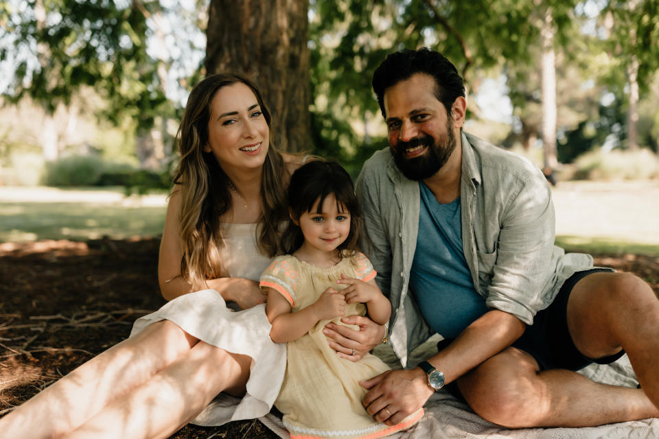 Dutch citizen Natalie (left) sits under a tree with her husband Alex and daughter Rory who both have Australian passports sitting beside her. Source: Julia Forte 