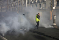 Yellow vest protesters walk through tear gas during a demonstration Saturday, Feb.16, 2019 in Paris. Yellow vest protesters are holding scattered demonstrations around Paris and the rest of France amid waning support for their movement. (AP Photo/Thibault Camus)