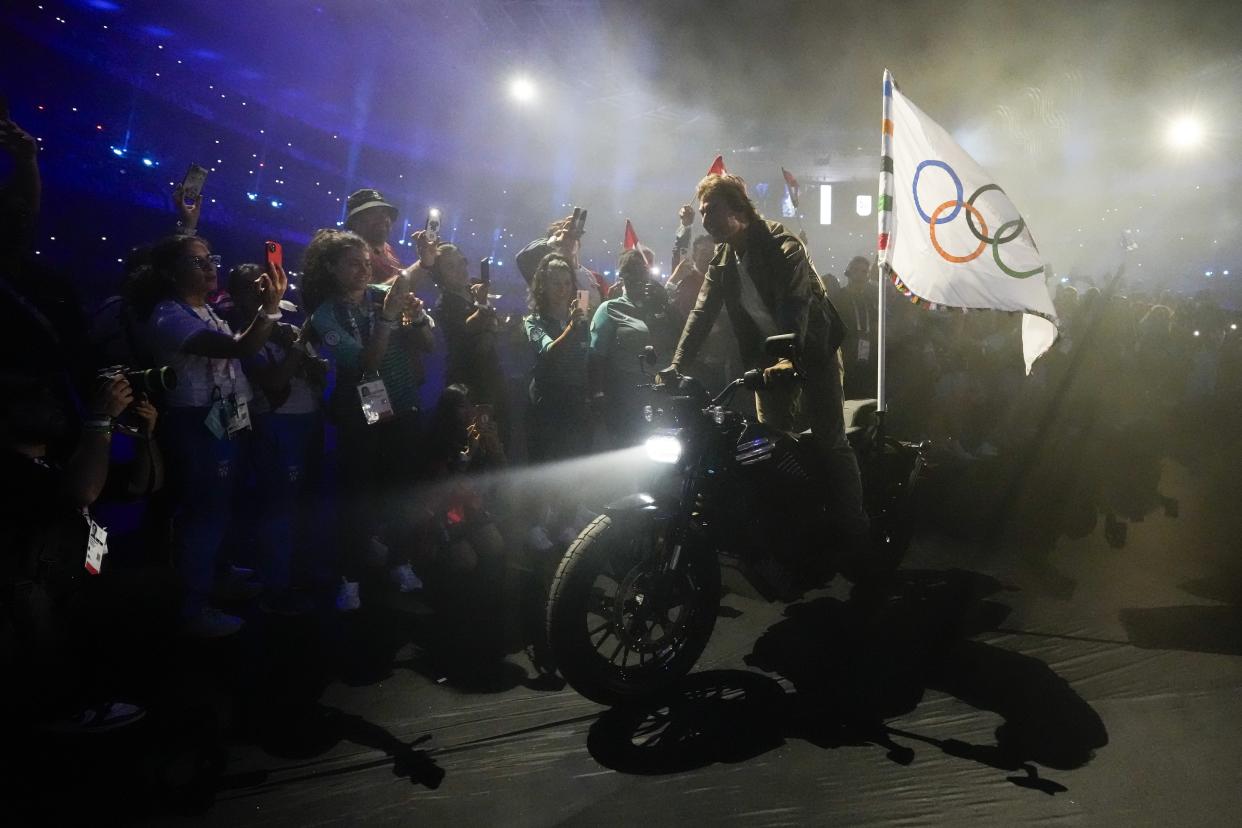 Tom Cruise rides a motorbike with the Olympic flag attached during the 2024 Summer Olympics closing ceremony at the Stade de France, Sunday, Aug. 11, 2024, in Saint-Denis, France. (AP Photo/Ashley Landis)