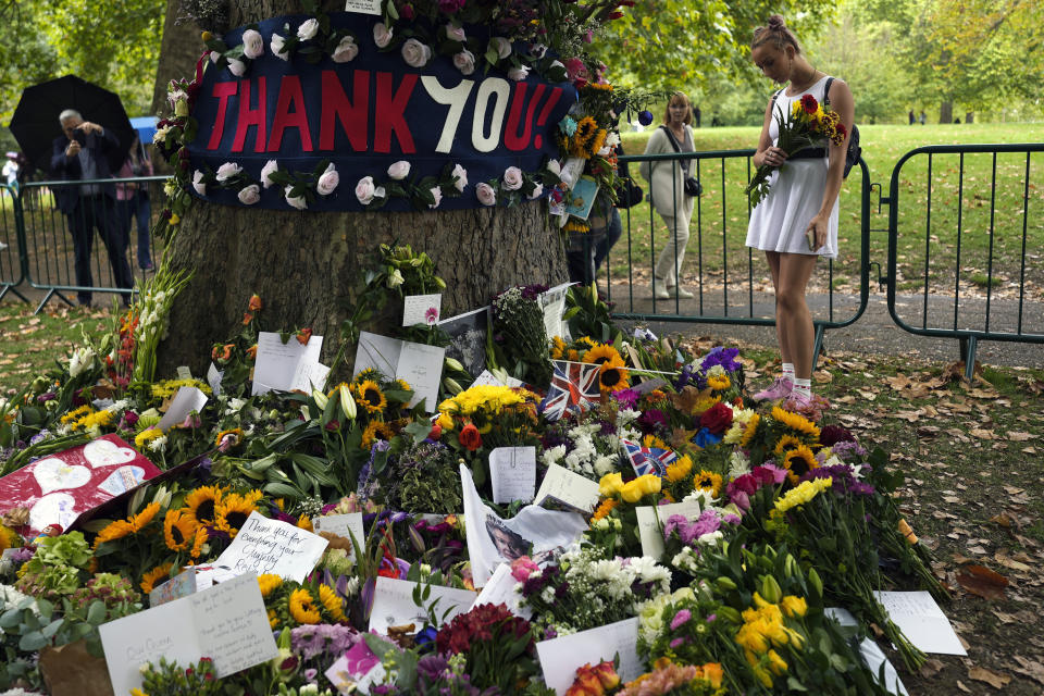 A woman reads messages placed between flowers for late Queen Elizabeth II at Green Park, near Buckingham Palace in London, Tuesday, Sept. 13, 2022. Because she reigned and lived for so long, Queen Elizabeth II's death was a reminder that mortality and the march of time are inexorable. (AP Photo/Markus Schreiber)
