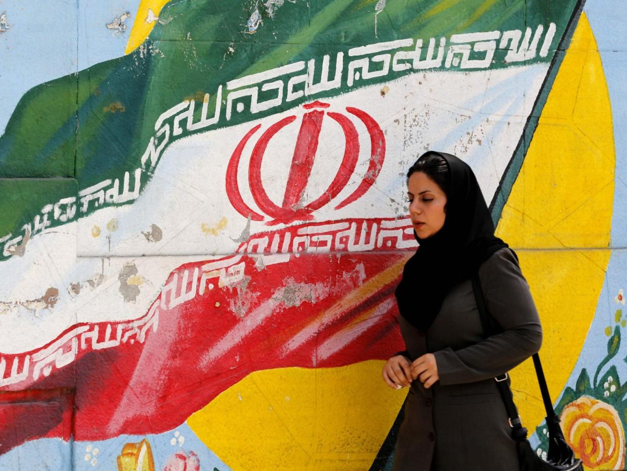 A woman walks in front of a mural painting depicting the Iranian flag, in the capital Tehran on August 6, 2018: AFP/Getty Images