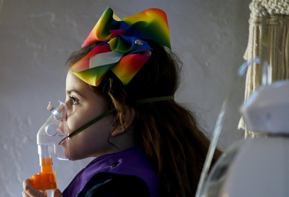 Scarlett Rasmussen, 8, uses an airway clearance system that uses vibrations to clear mucus from her lungs while getting ready for school, Wednesday, May 17, 2023, at their home in Grants Pass, Ore. Scarlett reads at her grade level, but is nonverbal and uses an electronic device and online videos to communicate. She was born with a genetic condition that causes her to have seizures and makes it hard for her to eat and digest food. Because of her medical needs, the school must have a resident nurse on site. (AP Photo/Lindsey Wasson)