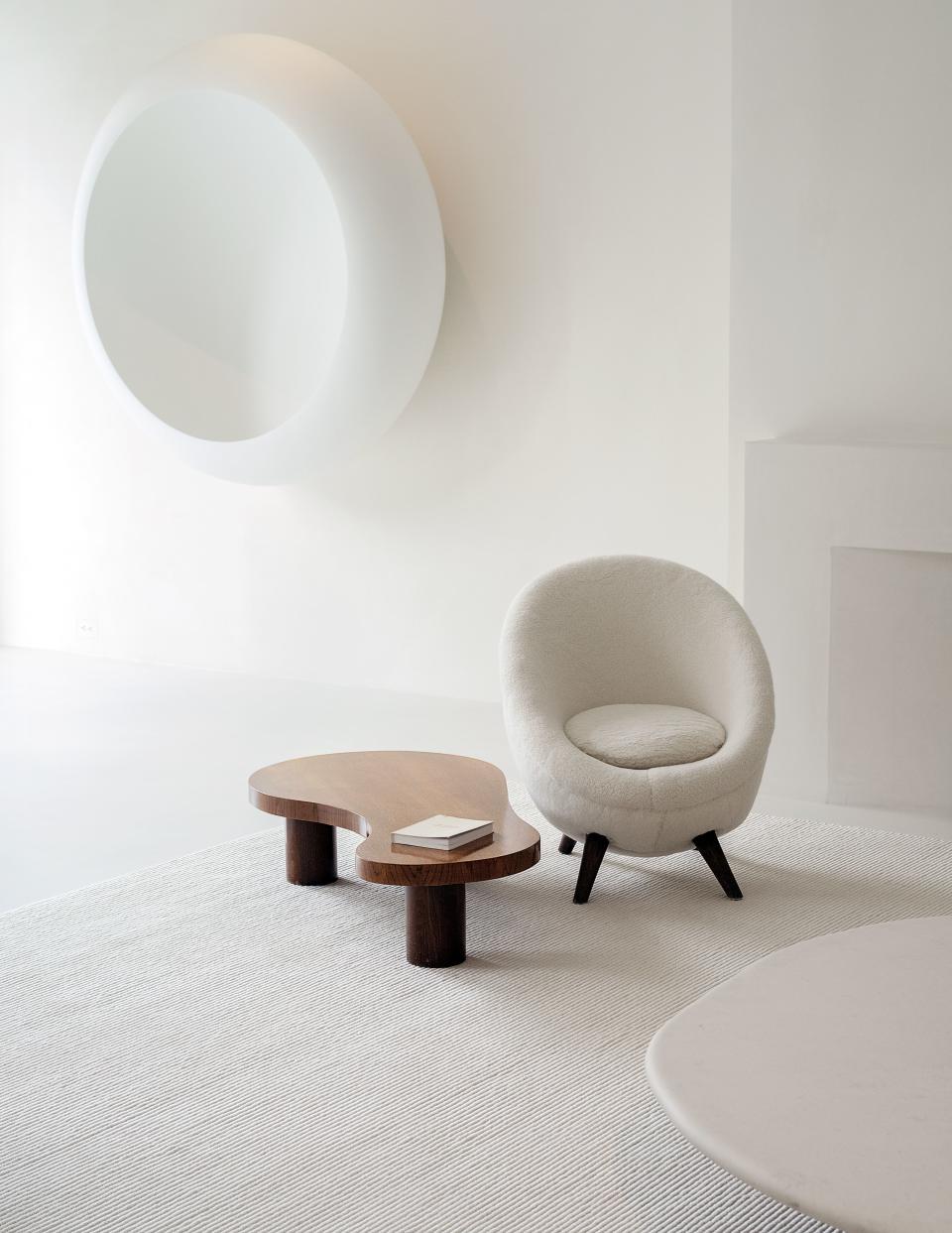 A Jean Royère chair and table in the living room. On wall, Anish Kapoor fiberglass sculpture.