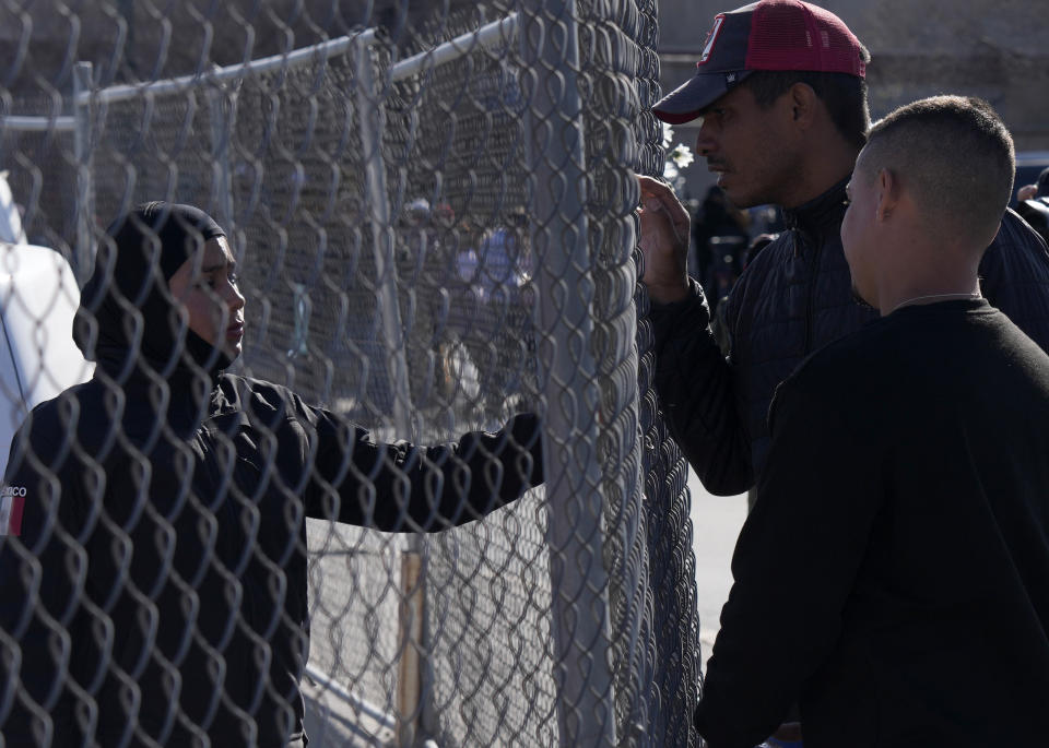 Migrants, right, as a member of the Mexican National Guard if there is any new information available regarding the victims of a fire at an immigration detention center that killed dozens, in Ciudad Juarez, Mexico, Tuesday, March 28, 2023. According to Mexican President Andres Manuel Lopez Obrador, migrants fearing deportation set mattresses ablaze at the center, starting the fire. (AP Photo/Fernando Llano)