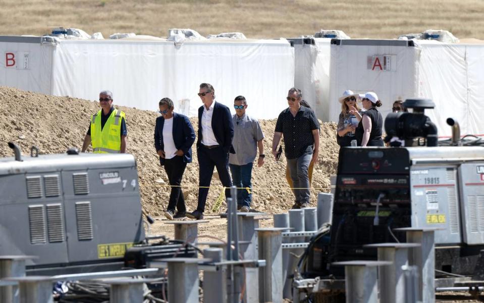 California Gov. Gavin Newsom, middle, tours a battery storage facility at the Proxima Solar Farm under construction outside Patterson, Calif., Friday, May 19, 2023. Newsom on Friday signed an executive order laying the groundwork for a bold plan to expedite major transportation, water, clean energy and other infrastructure projects across California.