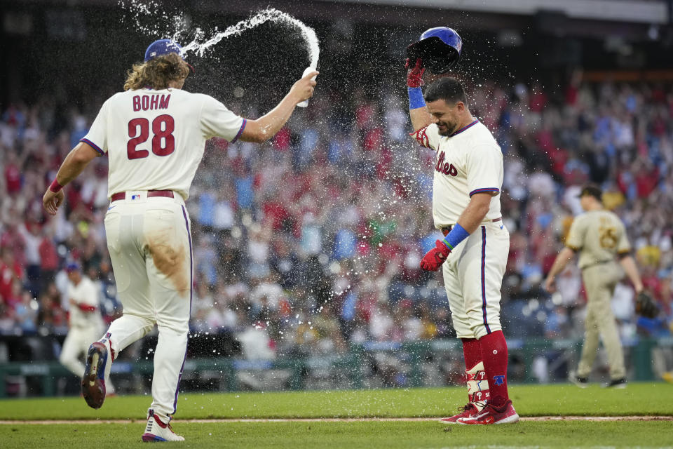 Philadelphia Phillies' Kyle Schwarber, center, celebrates with Alec Bohm, left, after hitting a game-winning RBI-sacrifice fly against San Diego Padres relief pitcher Tim Hill during the 12th inning of a baseball game, Sunday, July 16, 2023, in Philadelphia. (AP Photo/Matt Slocum)