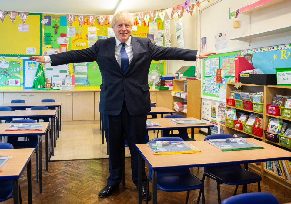 Image: Britain's Prime Minister Boris Johnson poses with his arms out-stretched in a classroom as he visits St Joseph's Catholic Primary School in Upminster, east London (Lucy Young / AFP - Getty Images)