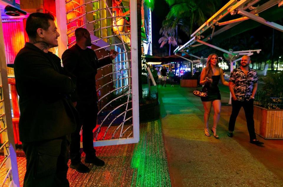 People make their way off Ocean Drive near Mango’s Tropical Cafe as police officers enforce a midnight curfew in Miami Beach, Florida on Friday, March 25, 2022. City officials imposed a midnight curfew and forced stores to stop selling alcohol after 6 p.m. The restrictions were set in place after two shootings in Miami Beach the weekend before caused city officials to announce a “state of emergency.”