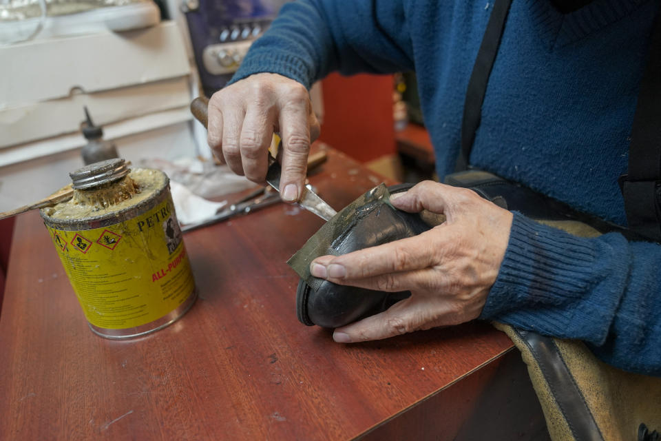 Jairo Cardenas, the owner the Alpha Shoe Repair Corp., repairs a boot, Friday, Feb. 3, 2023, in New York. Business at the shop, which Cardenas has run for 33 years, is down 75% compared with prior to the pandemic. Shoe repairs typically bring in more money than shines. (AP Photo/Mary Altaffer)