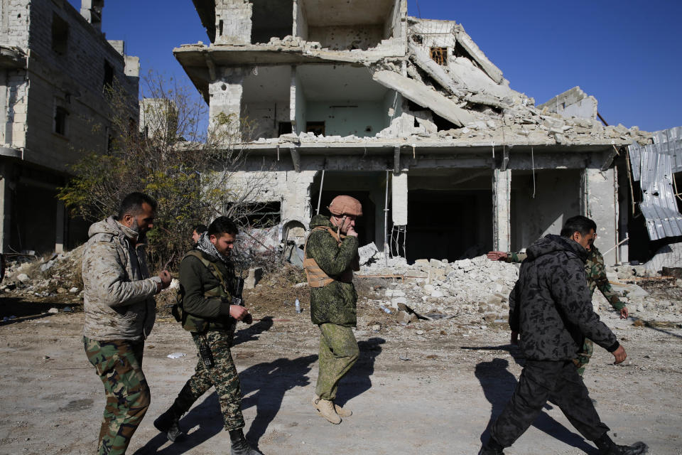 FILE - Russian and Syrian army soldiers gather at the last checkpoint before the front line with rebels, in Karam al-Tarab, east of Aleppo, Syria, Dec. 4, 2016. Political observers say Russia’s brazen Syria intervention emboldened Putin, giving him a renewed Middle East foothold and helped pave the way for his current attack on Ukraine. (AP Photo/Hassan Ammar, File)