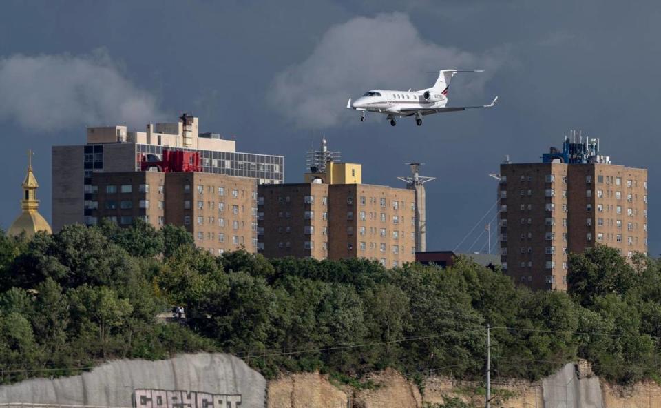 An Embraer Phenom 300 dips down below the level of nearby apartment buildings as it comes in for a landing at the Charles B. Wheeler Downtown Airport.