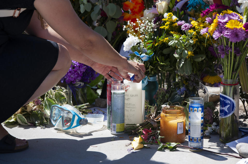 A woman relights a candle placed at a memorial for the victims of the Conception dive boat on the Santa Barbara Harbor on Sunday, Sept. 8, 2019 in Santa Barbara, Calif. Authorities served search warrants Sunday at the Southern California company that owned the scuba diving boat that caught fire and killed 34 people last week. Thirty-four people died when the Conception burned and sank before dawn on Sept. 2. They were sleeping in a cramped bunkroom below the main deck and their escape routes were blocked by fire. (AP Photo/Christian Monterrosa)