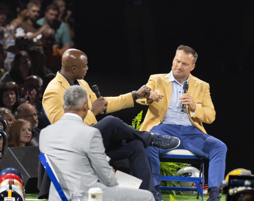 New Hall of Famers DeMarcus Ware (left) and Zach Thomas bump fists during the Enshrinees’ Roundtable on Sunday.