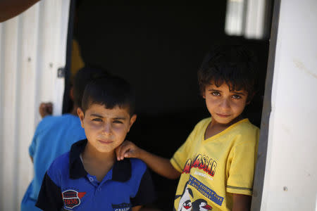 Syrian refugee children stand in front of their family residence at Azraq refugee camp near Al Azraq, east of Amman, August 19, 2014. REUTERS/Muhammad Hamed