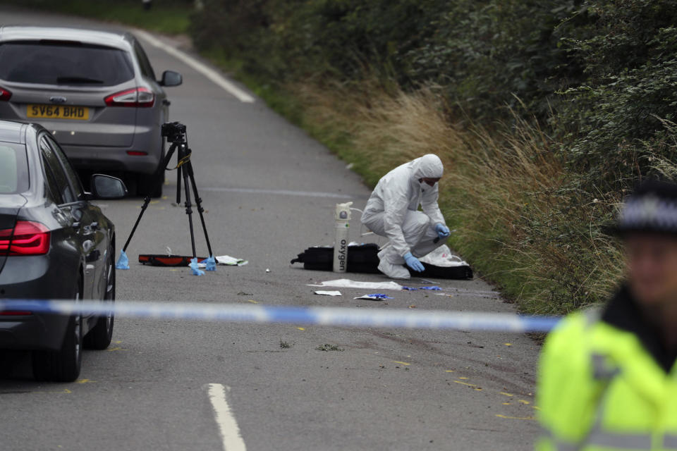 A police investigator at the scene of an incident where a police officer was killed, near Sulhamstead, England, Friday, Aug. 16, 2019. Thames Valley police say a British police officer investigating a reported burglary has been killed. Ten males have been arrested and are in custody, including a 13-year-old. Authorities say police Constable Andrew Harper of the Roads Policing Proactive unit was killed while "performing his duties" on Thursday night near the A4 between Reading and Newbury, in southeast England. (Steve Parsons/PA via AP)