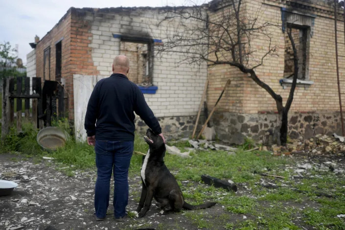 Eduard Zelenskyy pets his dog at his home destroyed by attacks in Potashnya, on the outskirts of Kyiv, Ukraine, Tuesday, May 31, 2022. Zelenskyy just returned to his home town after escaping war to find out he is homeless. (AP Photo/Natacha Pisarenko)