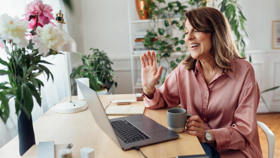 Smiling mature woman attending an online meeting from the comfort of her home office.